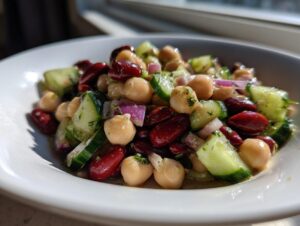 Close-up of a vibrant bowl of high protein bean salad featuring chickpeas, kidney beans, cucumber, and red onion.