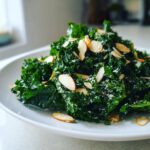 Close-up of a vibrant kale salad topped with sliced almonds and grated cheese.