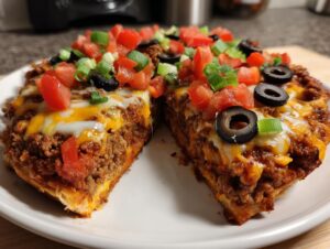 A thick slice of homemade mexican pizza showing layers of seasoned beef, melted cheese, topped with diced tomatoes, black olives, and green onions.