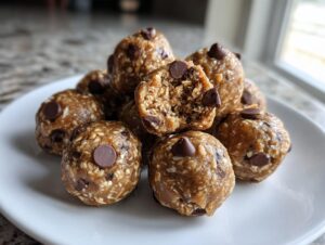 A pile of homemade peanut butter protein balls studded with chocolate chips on a white plate.
