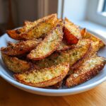 A close-up of golden brown, crispy potato wedges seasoned with garlic and Parmesan cheese.